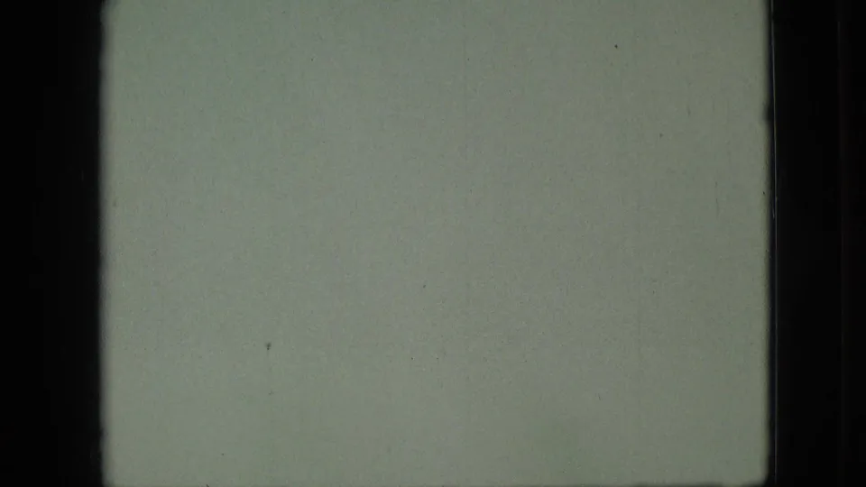 1968 Branson, Missouri home-movie frame with a pale hazy water or sky area, dark film-gate borders, grain, small specks, and a dim greenish cast.