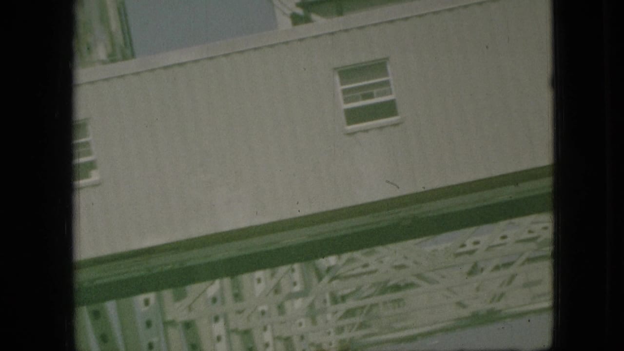 1968 Branson, Missouri home-movie frame showing a tilted pale building wall and structural framework glimpsed through dark window edges.