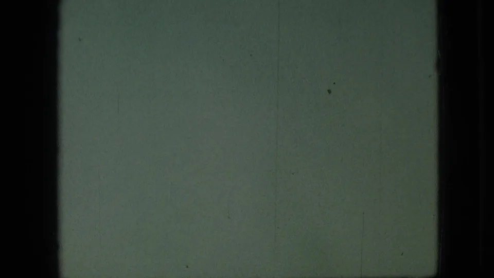 Green-tinted 8mm frame with little visible subject detail, bordered by dark vertical edges and faint film marks.