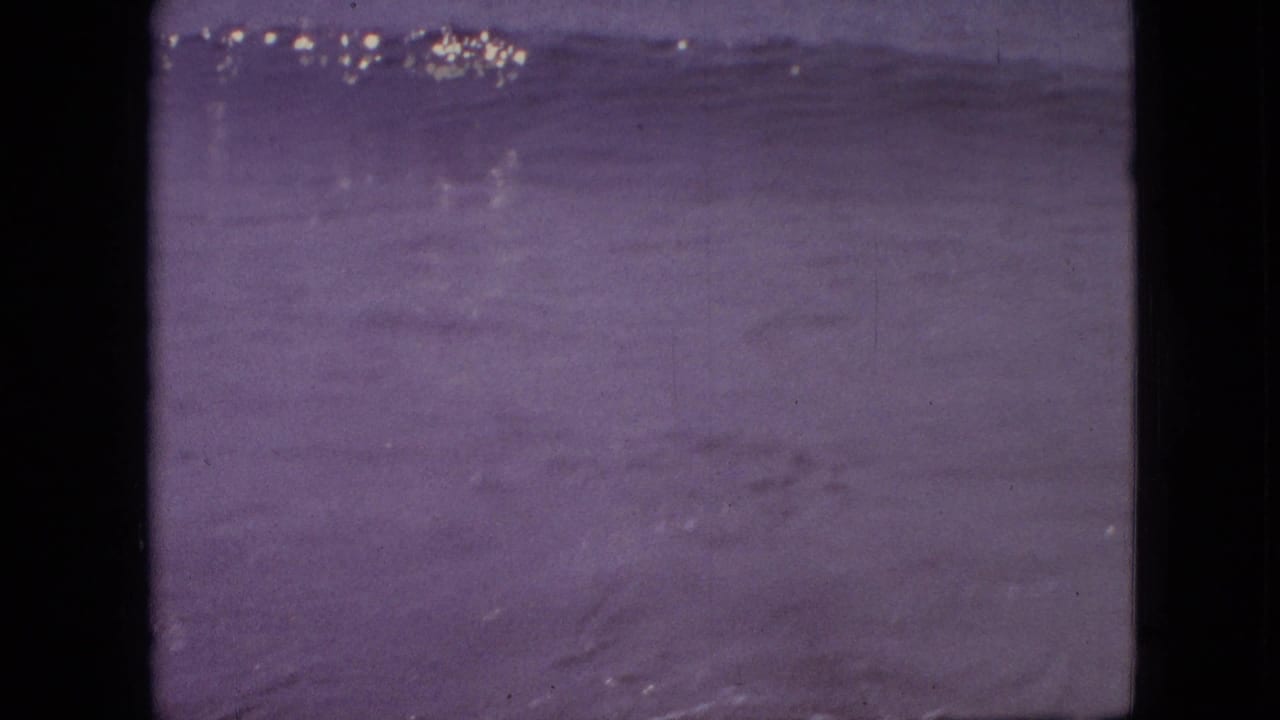 Soft purple-toned water surface with a low horizon and dark film borders.