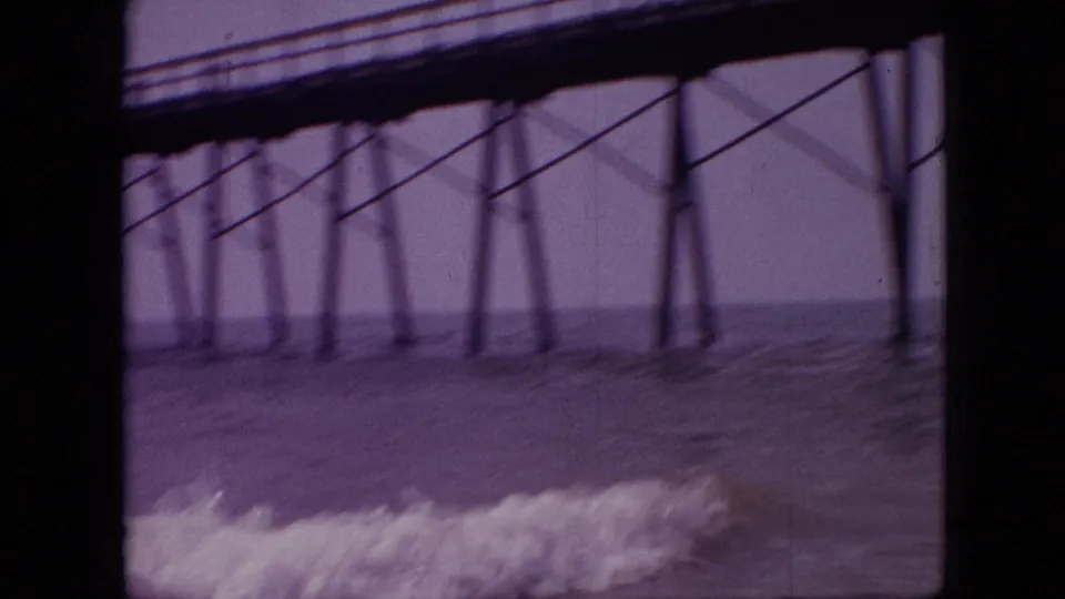 The camera looks along a wooden pier over moving water and shoreline waves in 1968 home-movie footage recorded as Branson, Missouri.