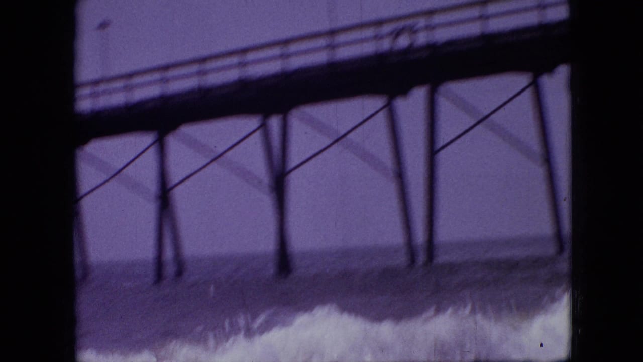 1968 8mm home-movie frame, cataloged as Branson, Missouri, showing a foamy wave rolling beneath dark pier beams and supports with open water in the background.