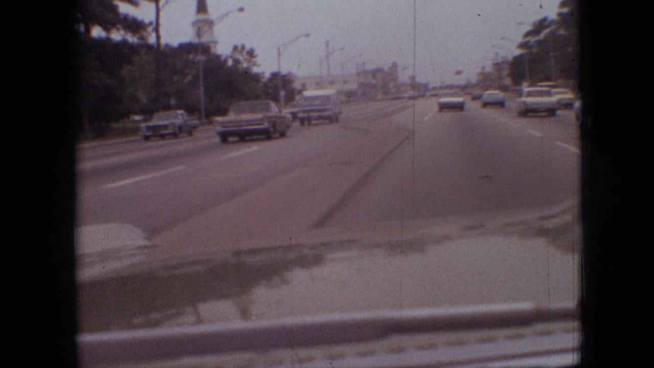 1968 Branson, Missouri driving footage showing several period cars on a multi-lane roadway with trees to the side and the filming vehicle's dashboard visible.