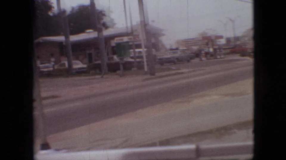 1968 Branson, Missouri frame with a gas station, canopy, cars, and roadside signage viewed from across a multi-lane road.