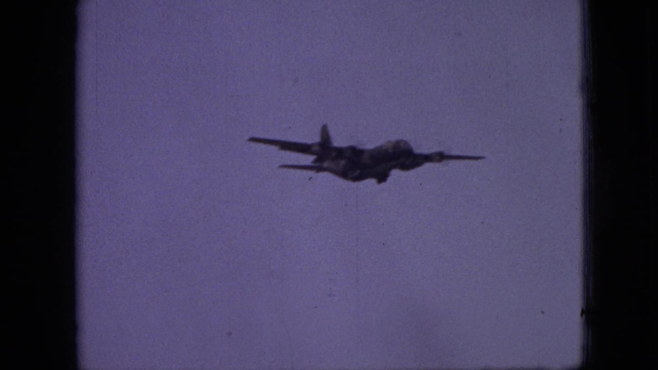 A propeller aircraft appears in silhouette against a pale purple sky in 1968 8mm home-movie footage from Branson, Missouri.