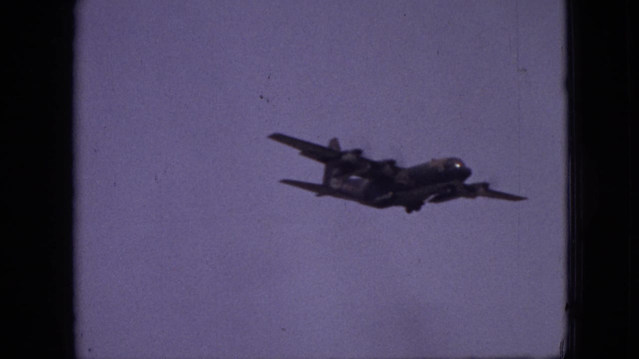 Twin-engine propeller plane flying across a pale sky.