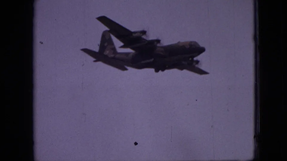 A closer underside view shows the propeller aircraft with wings, tail, fuselage, and possible landing gear shapes against the pale sky.
