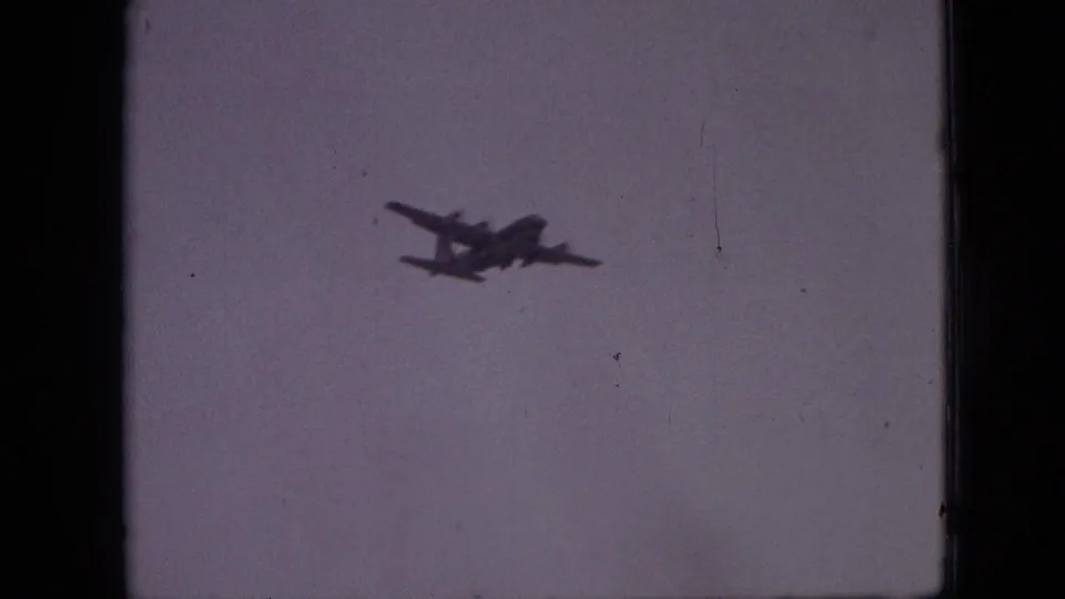 Distant four-engine aircraft appears as a dark silhouette against a pale sky in 1968 Branson, Missouri home-movie footage.