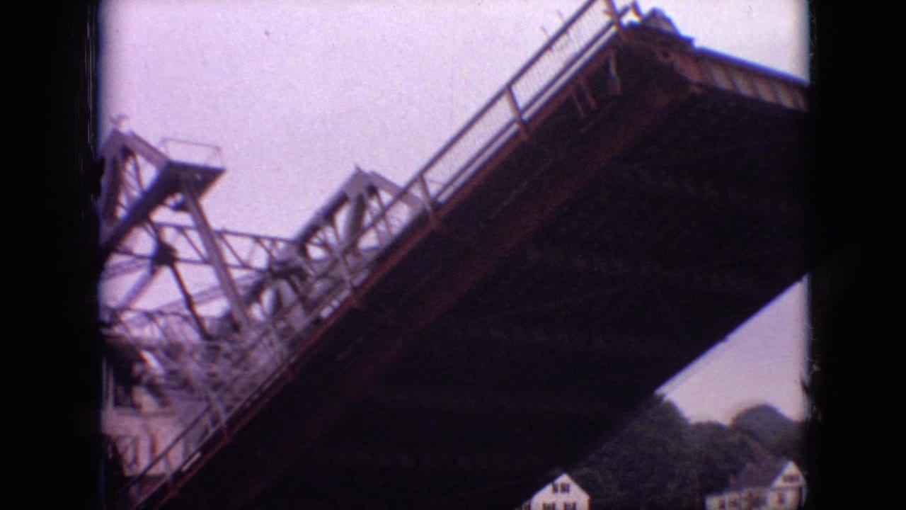 Steel drawbridge structure tilted upward against a pale sky with trees below.