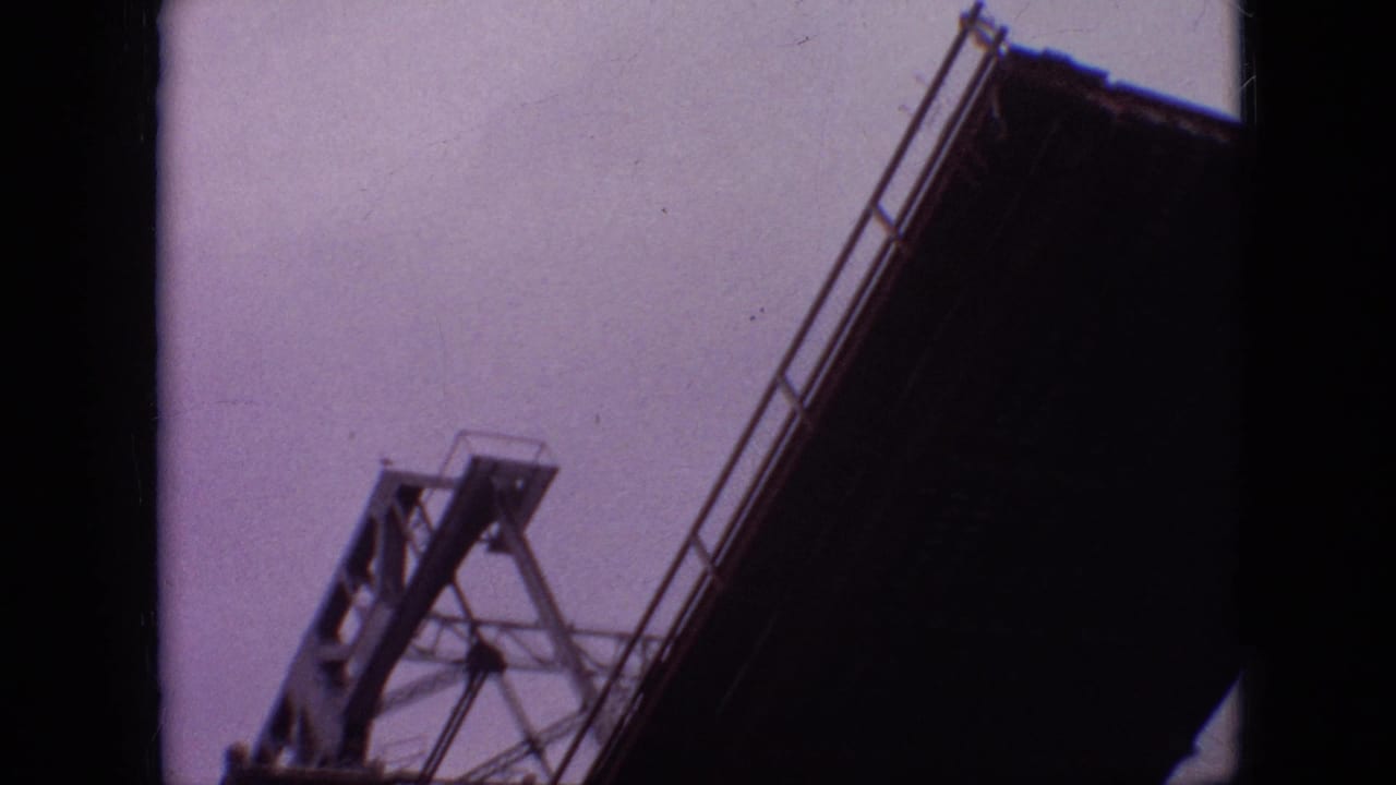 1968 Branson, Missouri 8mm frame showing the underside and lift structure of a raised red drawbridge against a pale sky.