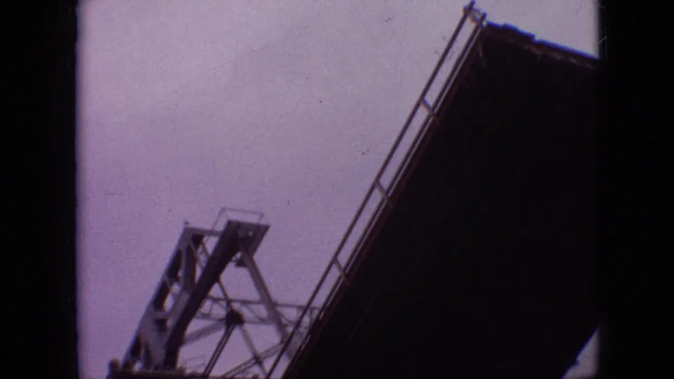 1968 Branson, Missouri 8mm frame showing the underside and lift structure of a raised red drawbridge against a pale sky.