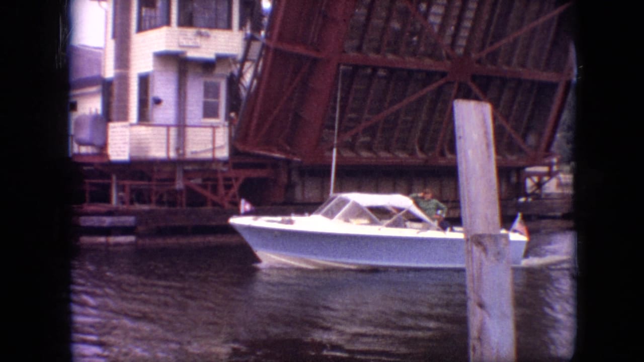 1968 Branson, Missouri 8mm frame showing a white motorboat on a canal beside a raised steel drawbridge and a small white bridge-control structure.