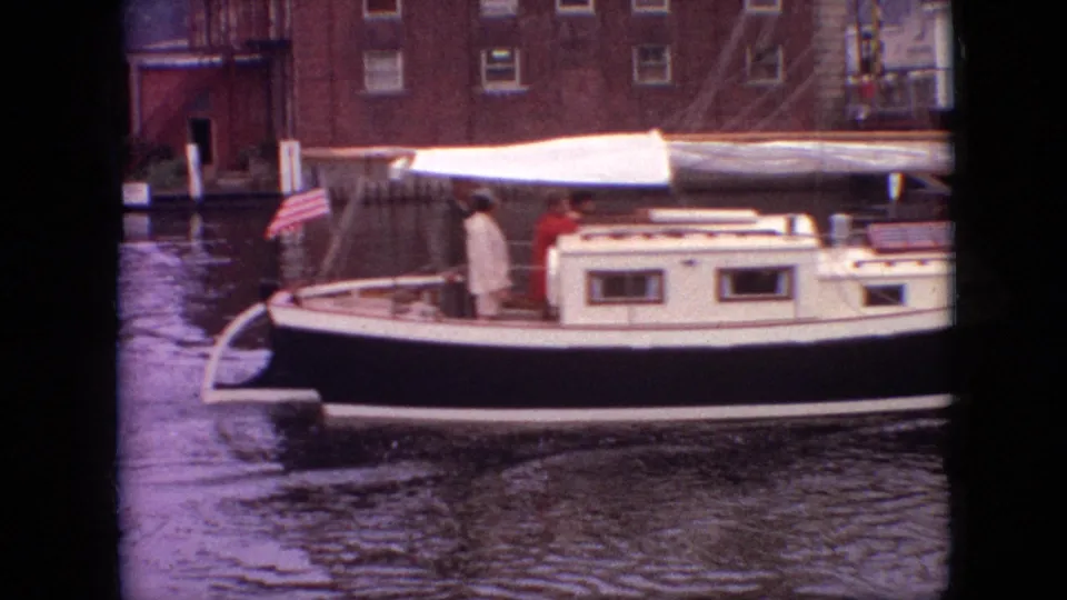 1968 Branson, Missouri 8mm frame showing a black-and-white sailboat with passengers, a white canopy, and a small American flag along a canal.