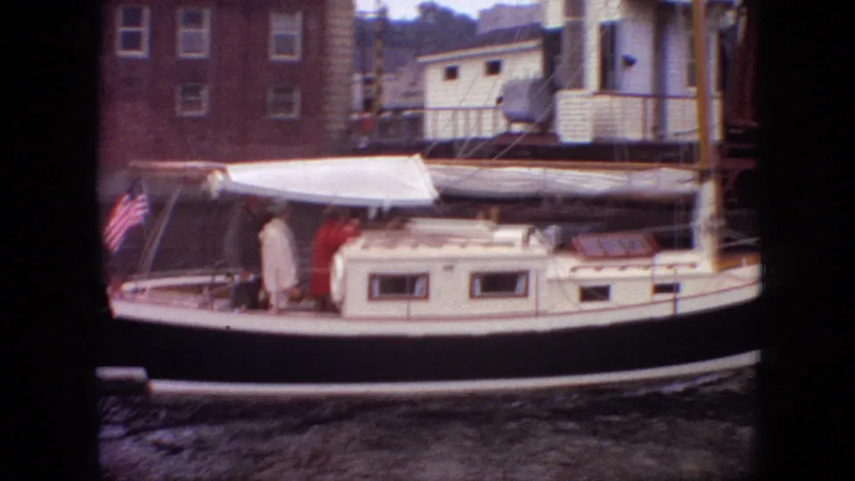 1968 Branson, Missouri 8mm frame showing a canopied sailboat passing close to the camera with passengers visible near the cabin and stern.