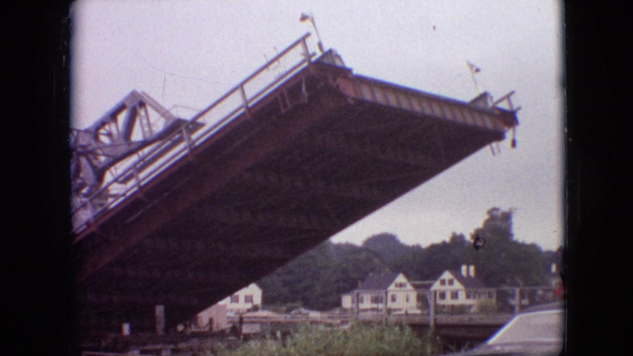 A low-angle 1968 Branson, Missouri 8mm frame shows a large steel drawbridge span still raised, with white riverside houses and trees beyond it.
