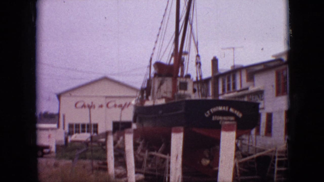 Boat stern and rigging beside a white building marked with Chris-Craft signage.