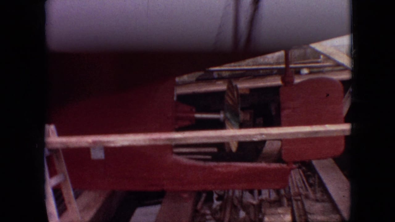 1968 Branson, Missouri home-movie frame showing a red vessel hull or boat section on land with railing, underside details, and dark film borders.