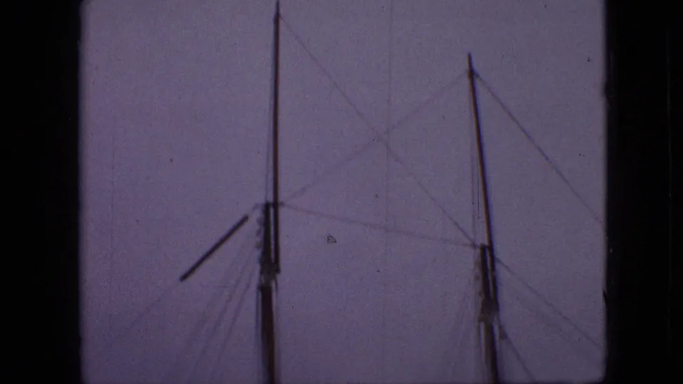 1968 Branson, Missouri footage frame with sailboat masts and fine rigging lines framed by dark edges in soft dusk light.