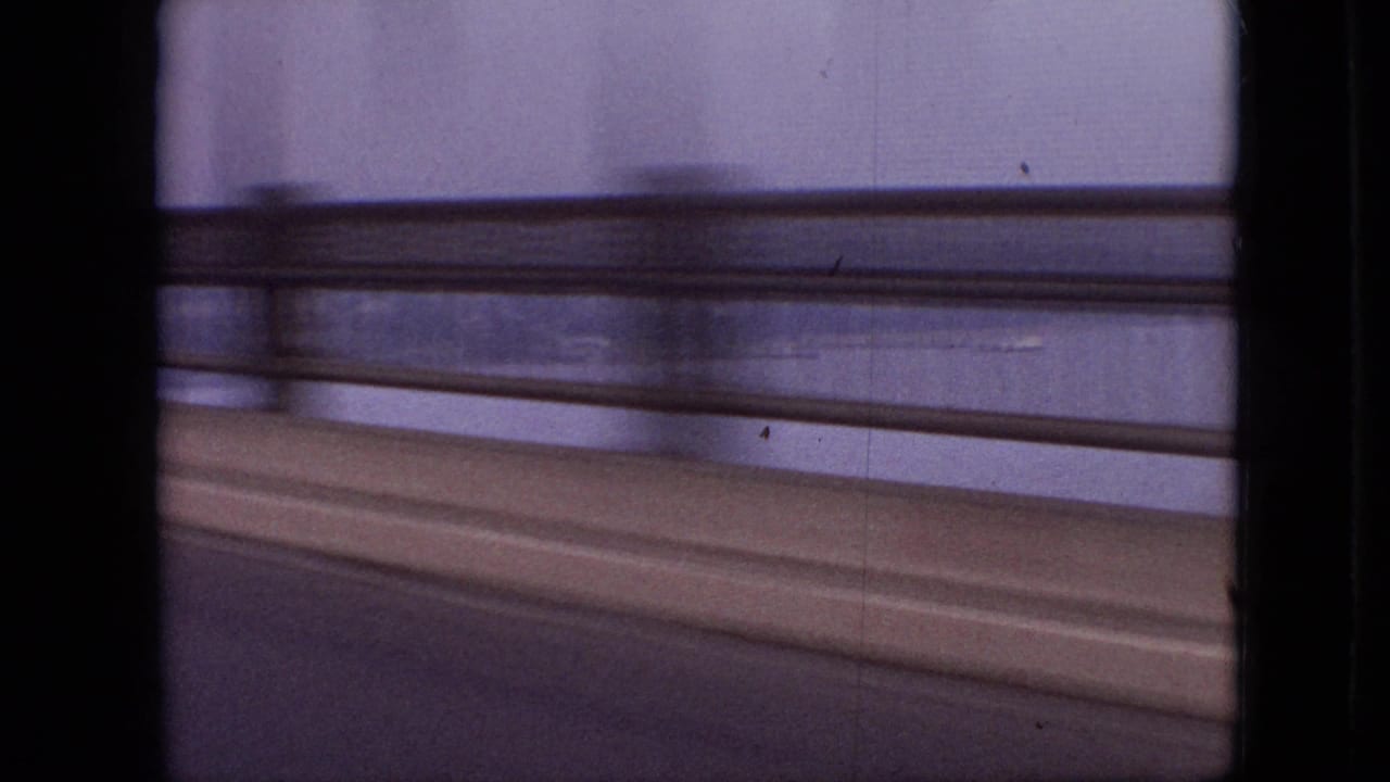 Blurred bridge railing and roadway seen from a moving vehicle.