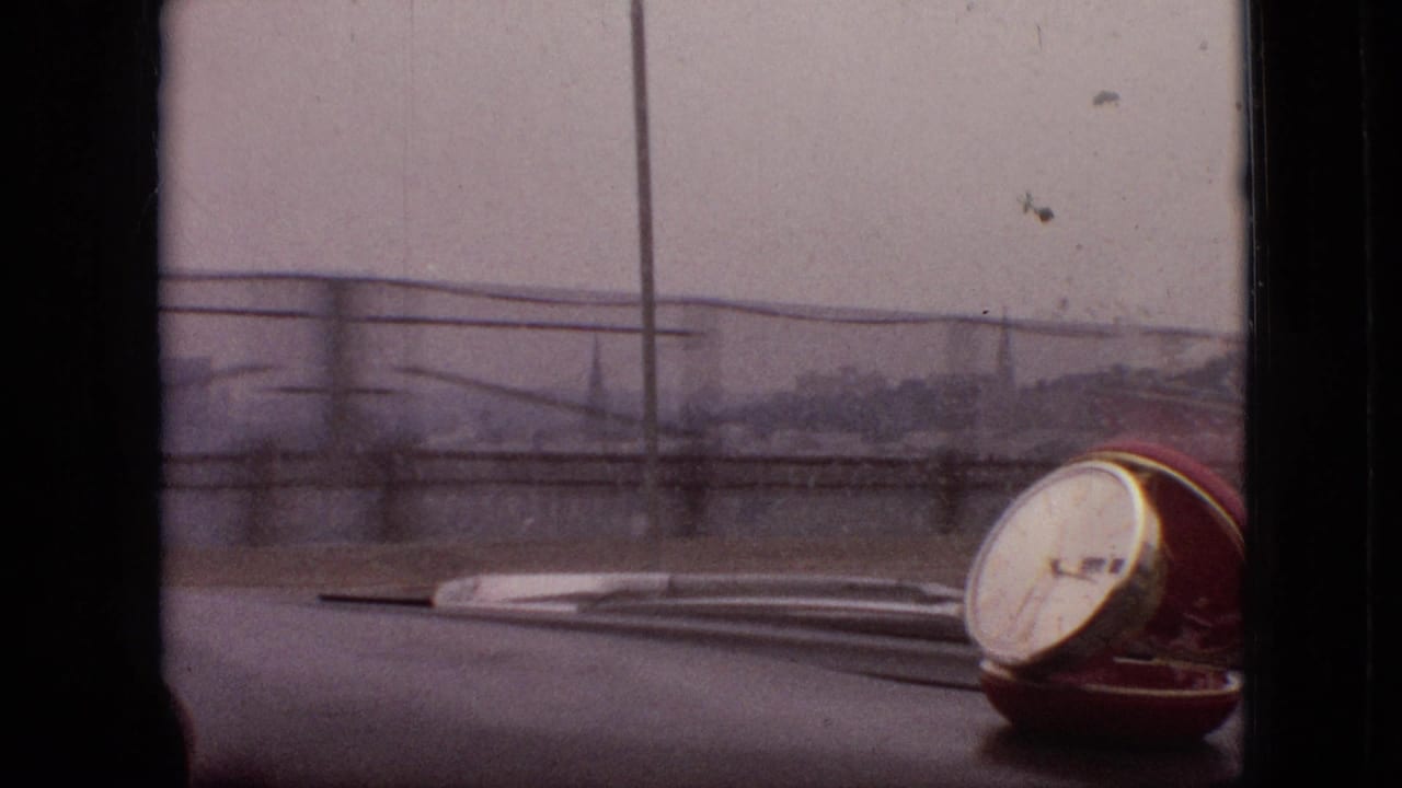 1968 Branson, Missouri home-movie frame from inside a car, showing the dashboard, windshield wipers, roadside railings, and a small red-and-white dashboard object through soft focus.