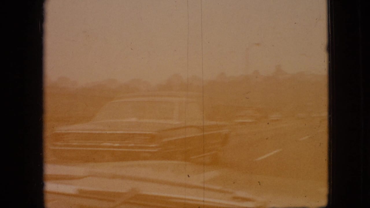 Sepia-toned road view with a pale older car seen through faded film.