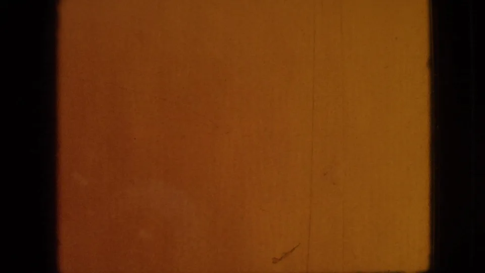 Warm orange 8mm end-frame from the 1968 Branson home movie, marked by color shift, scratches, dust, and dark physical film borders.