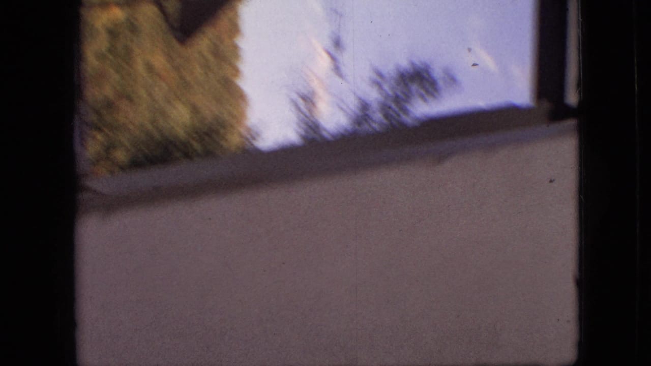 1968 Branson, Missouri 8mm frame with dark window framing, reflected trees, and a pale wall surface seen through soft home-movie focus.