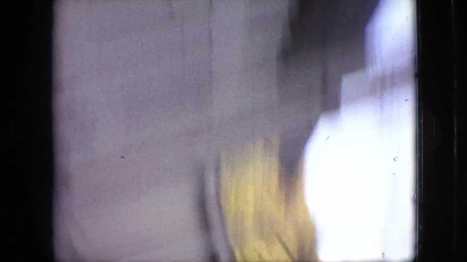 Soft, blurred 1968 Branson 8mm frame with a pale wall, bright window-side light, and dark film border suggesting quick handheld movement.
