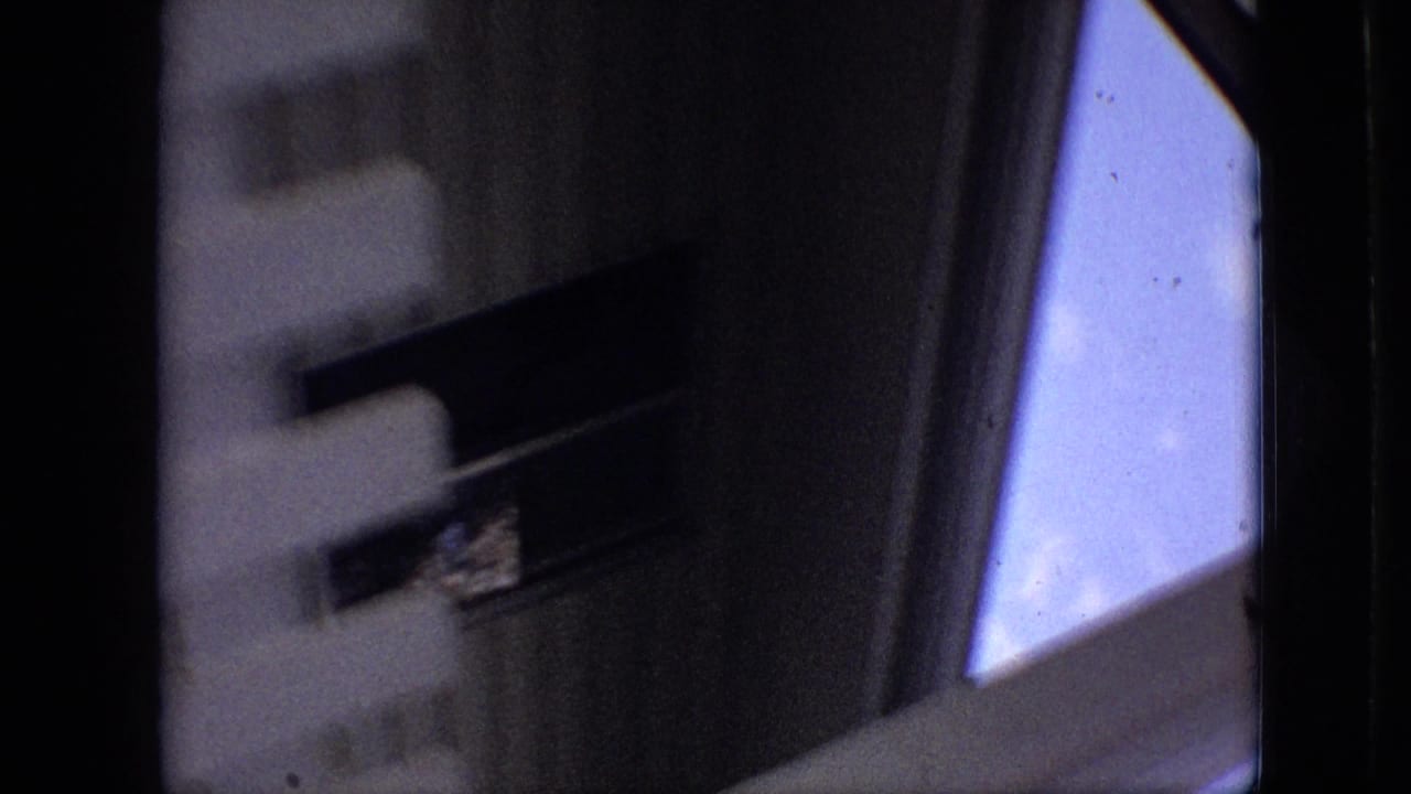 Dim 1968 8mm home-movie frame from Branson, Missouri, showing an interior edge, a white slatted or paneled structure, and daylight through a window.