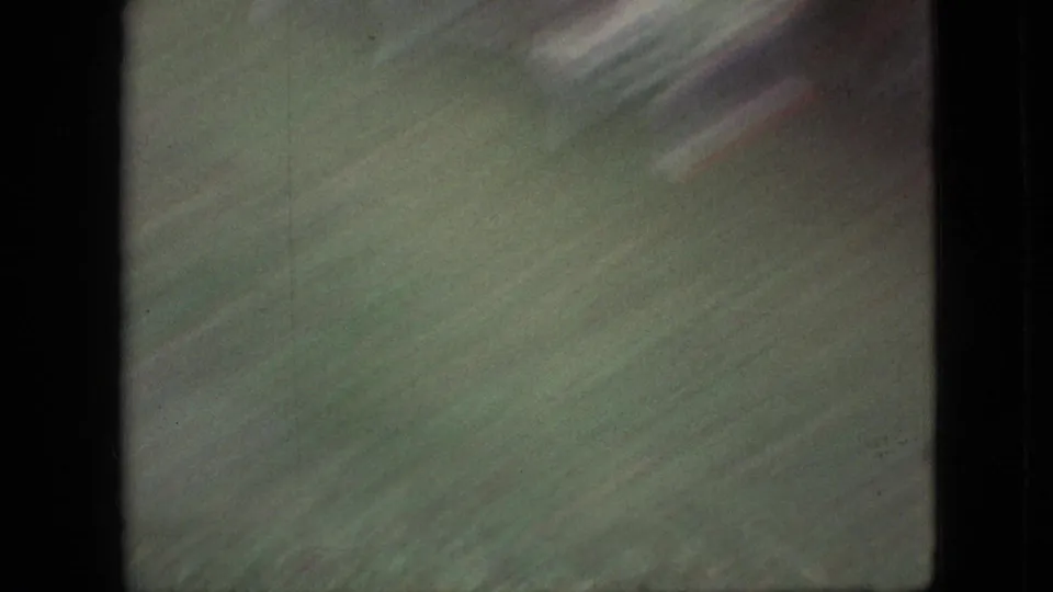 Soft, motion-blurred closing frame from the 1968 Branson backyard footage, dominated by green grass with faint yard detail and dark film edging.