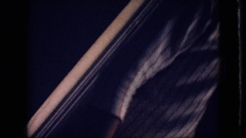 Close underexposed 1968 home-movie frame showing what appears to be a person’s striped garment or torso near the camera, with little surrounding detail visible.