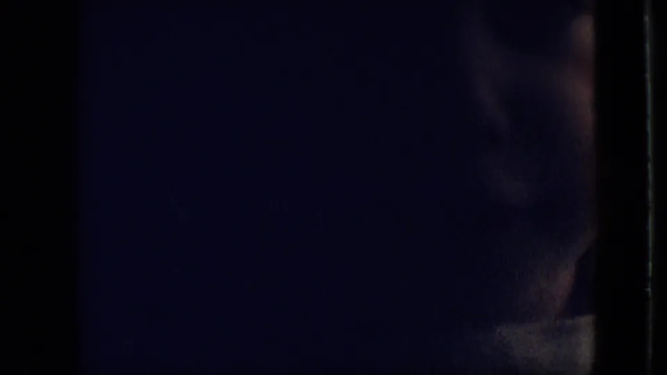 The toddler is seen in a very dark, blue-toned home-movie frame, with only part of the head and shoulder visible near the film edge.