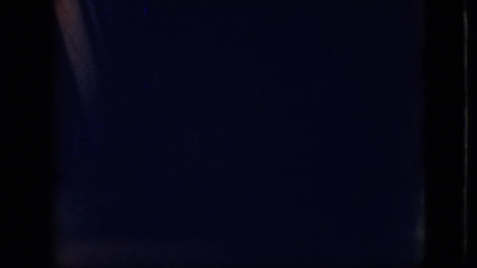 Underexposed 1968 8mm frame from the Branson, Missouri clip showing a mostly dark vehicle interior with faint blue and orange light along the film edge.