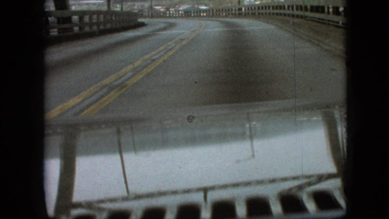 Driver point-of-view footage in Branson, Missouri, from supplied 1968 metadata, showing a two-way road curving across a bridge with the car hood visible at the bottom.