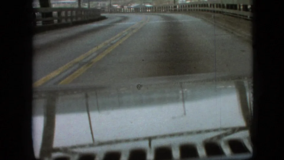 Driver point-of-view footage in Branson, Missouri, from supplied 1968 metadata, showing a two-way road curving across a bridge with the car hood visible at the bottom.