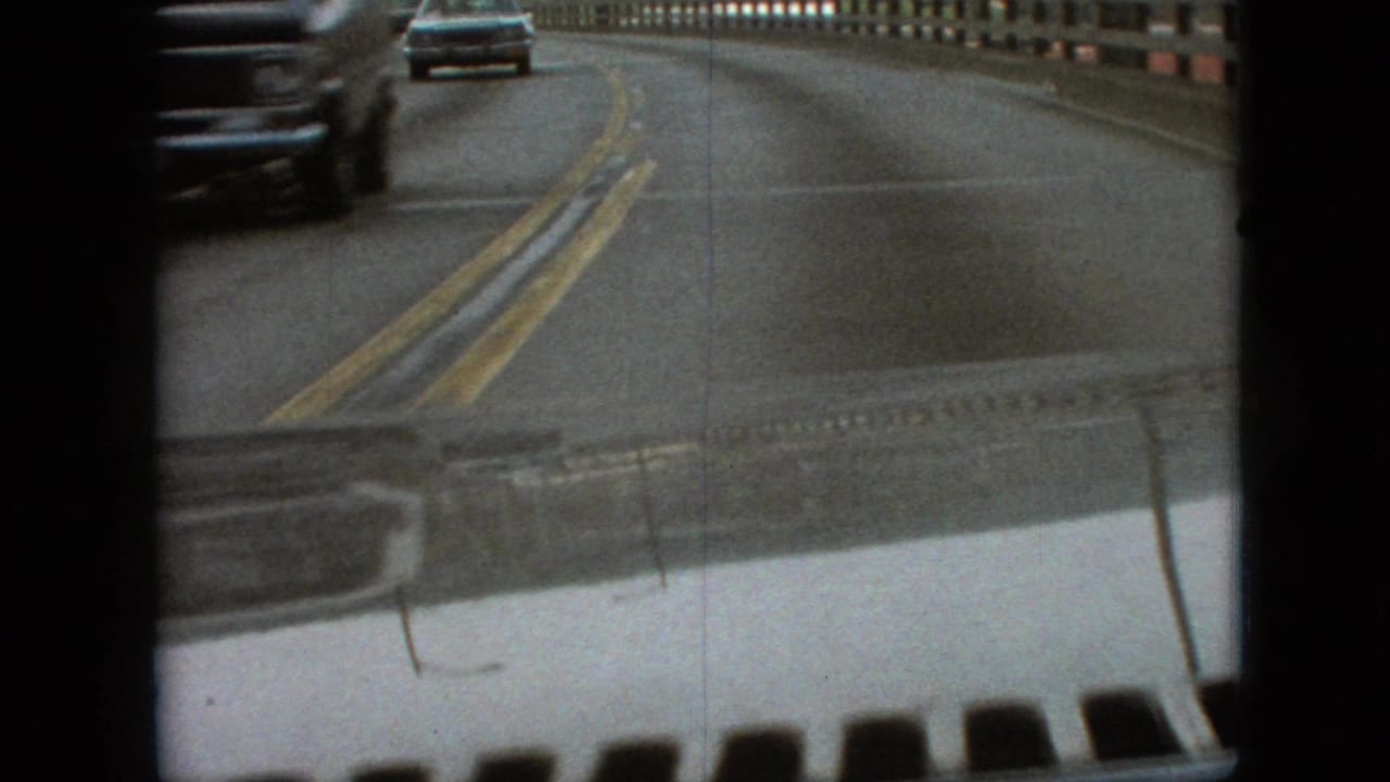 Bridge roadway seen from inside a car as another vehicle passes near the left edge.