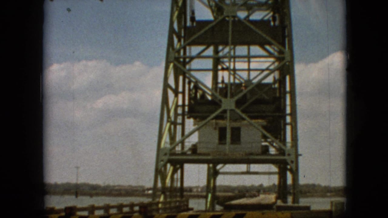 1968 8mm home-movie frame from Branson, Missouri, showing a green steel bridge structure next to open water and a distant shoreline.
