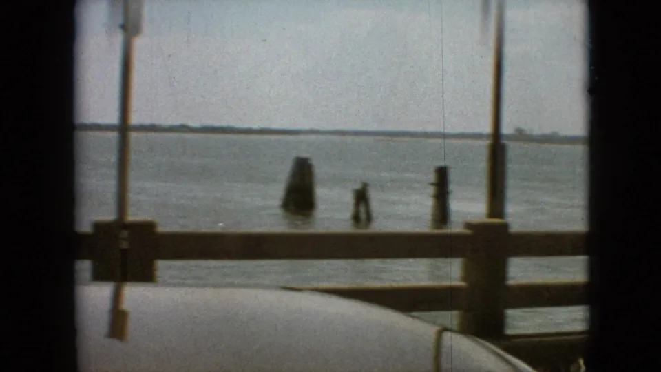 Final frame looking past bridge posts and railings toward lake water, channel markers, and a distant shoreline near Branson, Missouri in 1968.