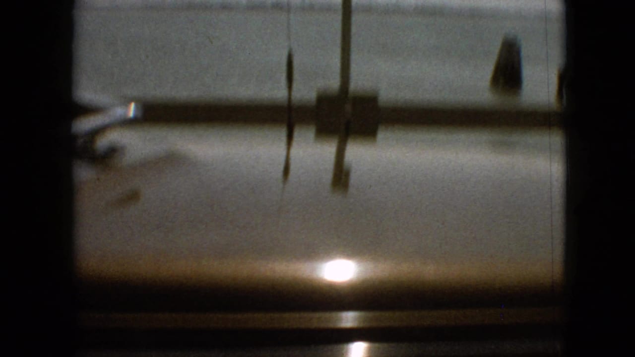1968 8mm frame from the Missouri travel clip showing a dark passenger-window or windshield view with reflected sunlight and indistinct exterior scenery beyond the glass.