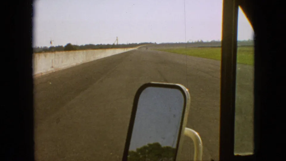Passenger-side truck view in supplied 1968 Branson, Missouri footage, with the mirror, road surface, concrete barrier, and open farmland visible.
