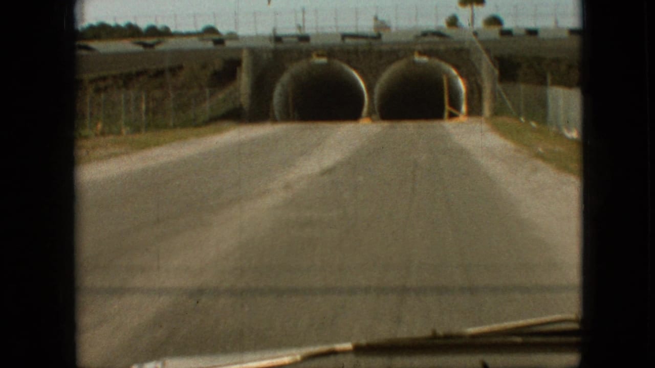 1968 Branson, Missouri home-movie frame from inside a car approaching a dual tunnel underpass on a sunny paved road.