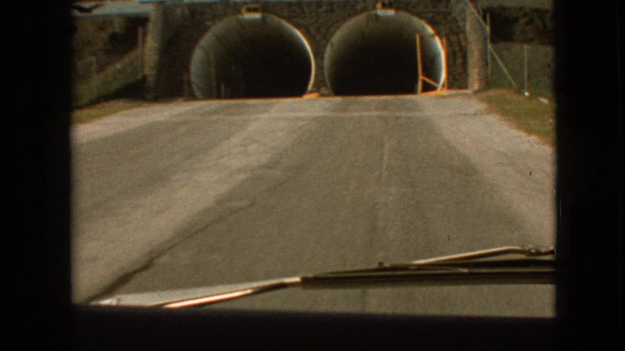 Closer windshield view of two round tunnel entrances ahead.