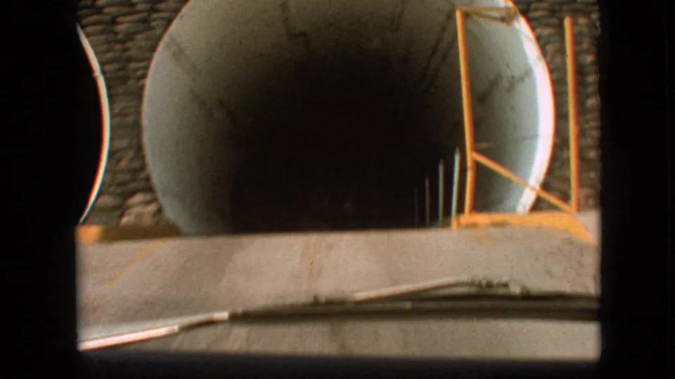 At the end of the clip, the car reaches the tunnel entrance, with the right circular opening and yellow edge structure dominating the 1968 Branson road view.