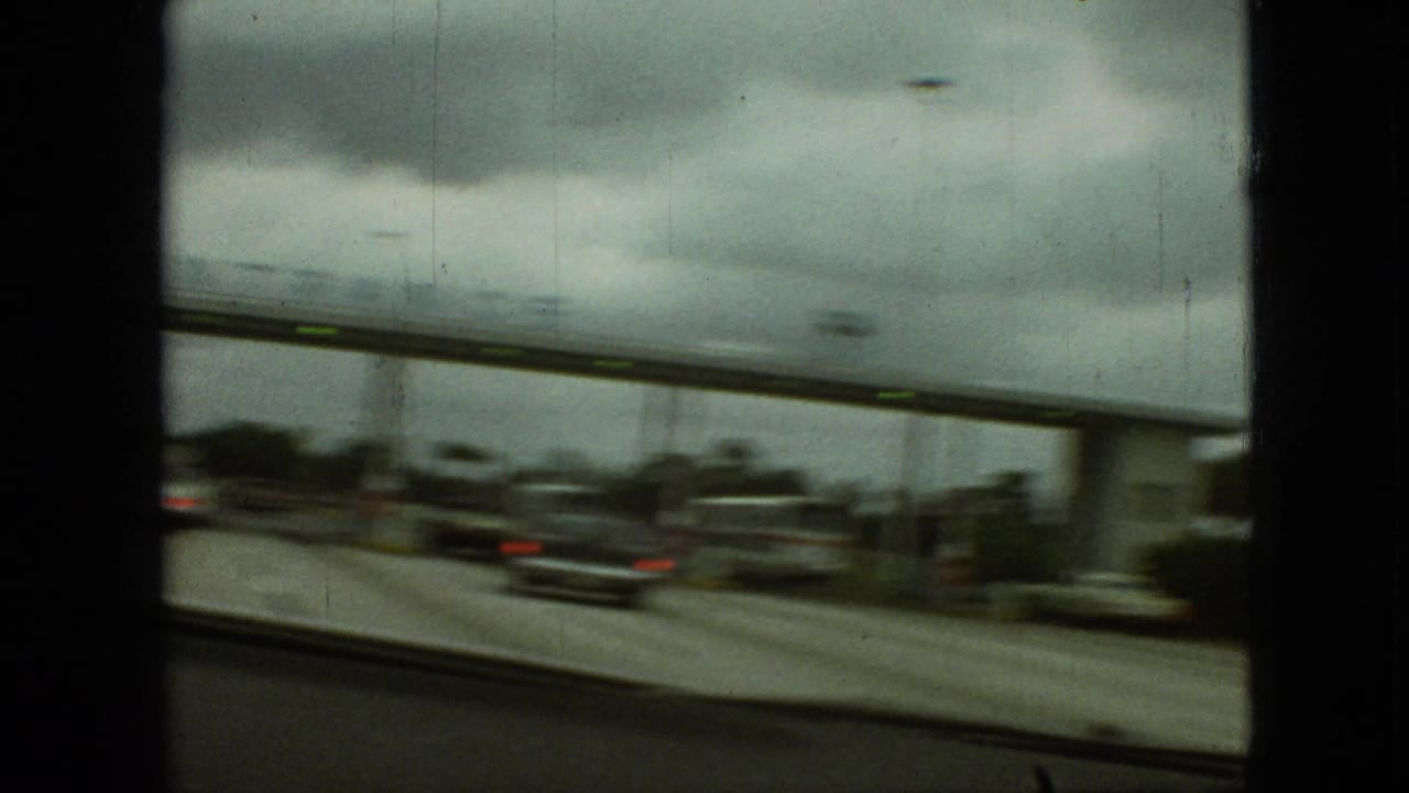 A blurred side-window view shows cars passing near an entrance structure.