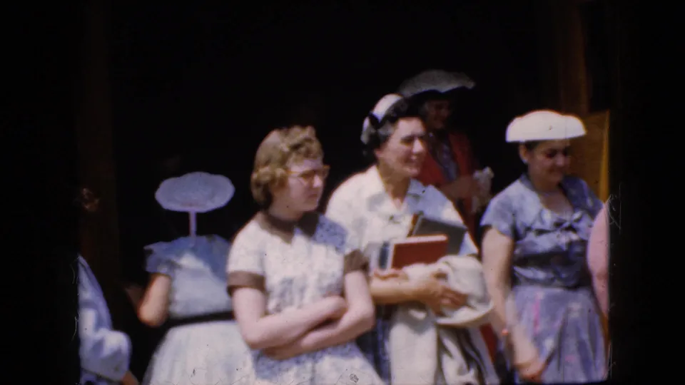 1969 California 8mm frame showing women leaving or standing near a church entrance, including women in hats and glasses and one holding books.