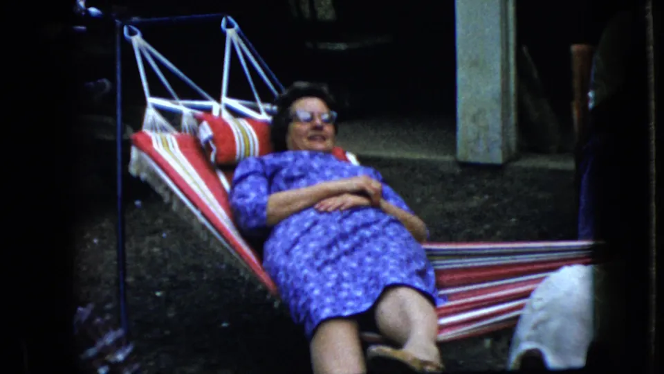 The final 1969 California frame shows the woman reclined in the striped hammock near porch or yard supports, with the home-movie frame cropped tightly around her.