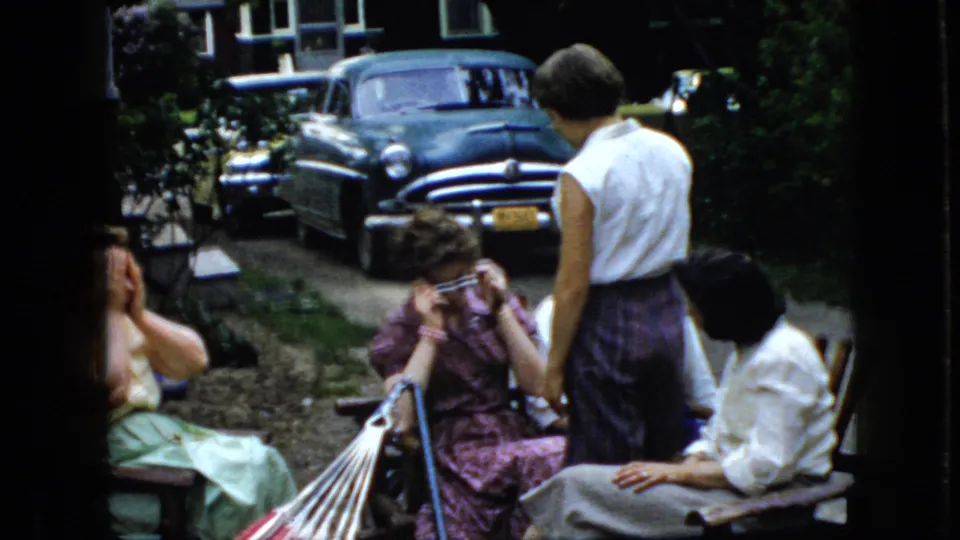 The final frame shows a woman adjusting her glasses near a striped hammock as other women sit close by, with a parked dark sedan and residential greenery in the background.