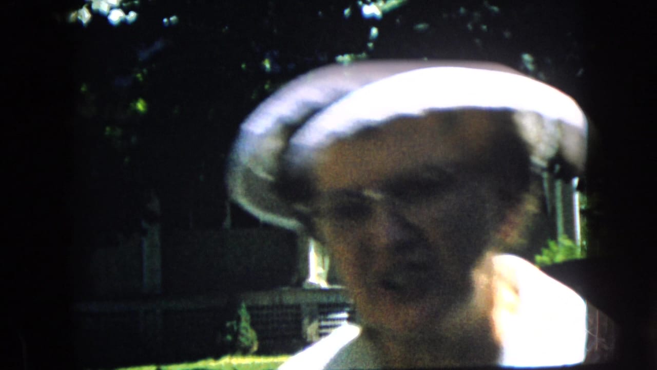 In this California 1969 8mm frame, an older woman wearing a white hat appears very close to the camera, with her face partly soft from motion and strong sunlight.