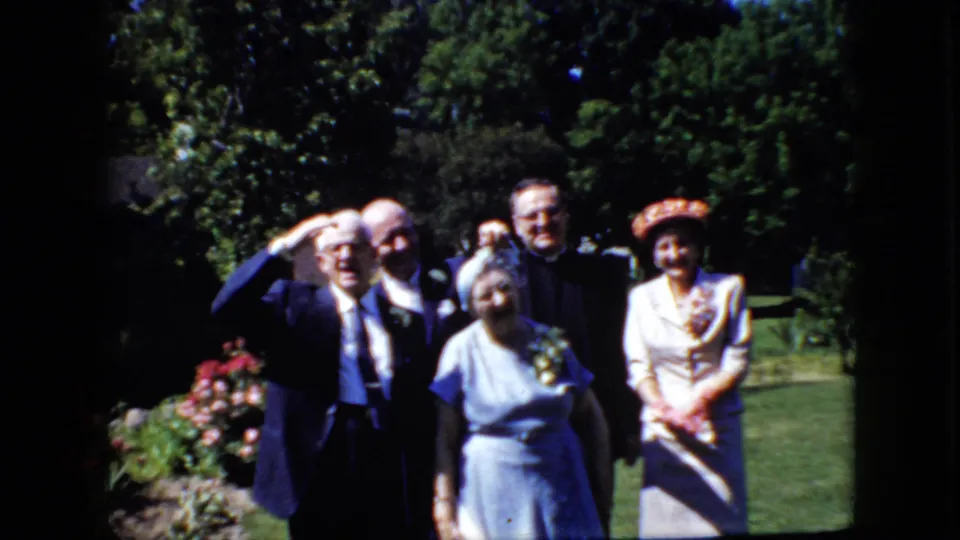 A 1969 California garden portrait shows adults in formal clothing facing the home-movie camera, including a woman in a light blue dress and another in a hat.