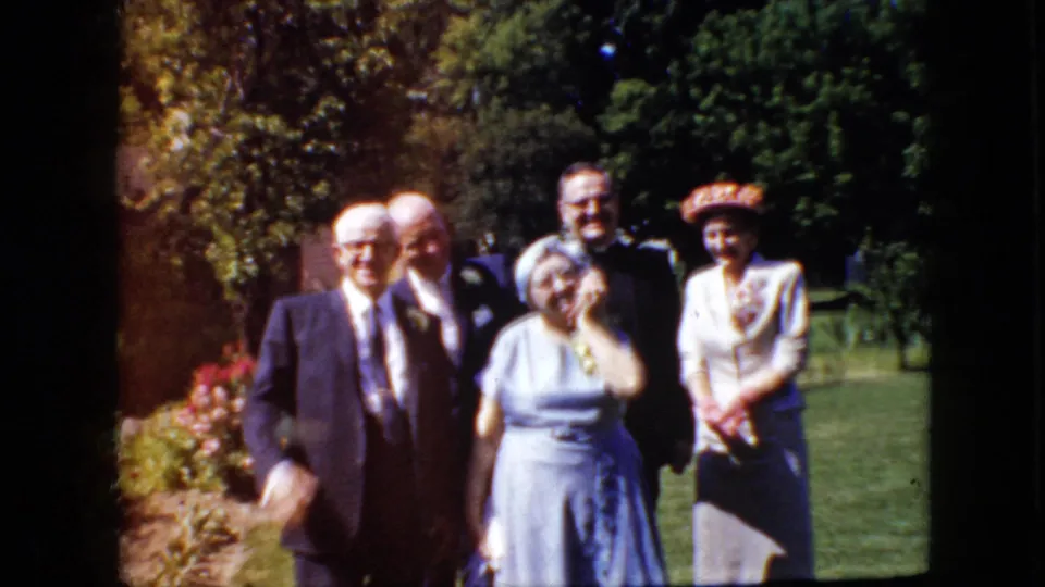 Near the end of the 1969 home-movie clip, formally dressed adults stand in the garden as one man moves in front of the group, creating motion blur.